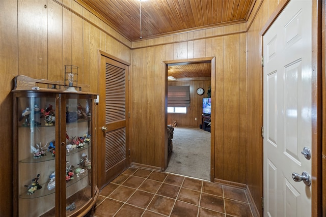 hall featuring dark carpet, wood walls, and wooden ceiling