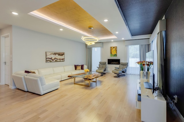 living room featuring a tray ceiling and light hardwood / wood-style flooring