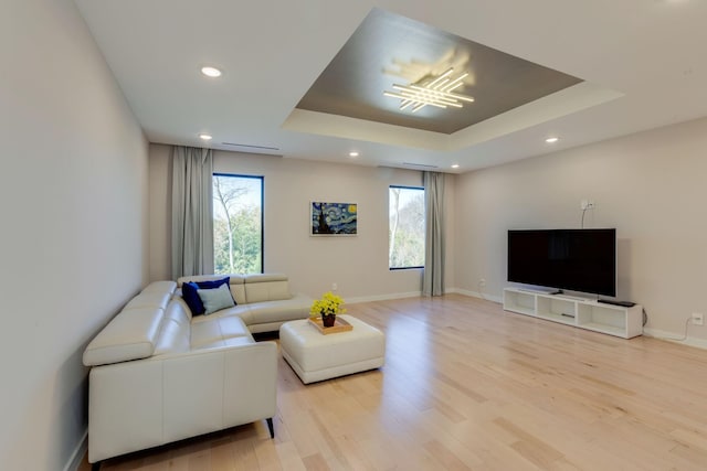 living room featuring a raised ceiling and light wood-type flooring