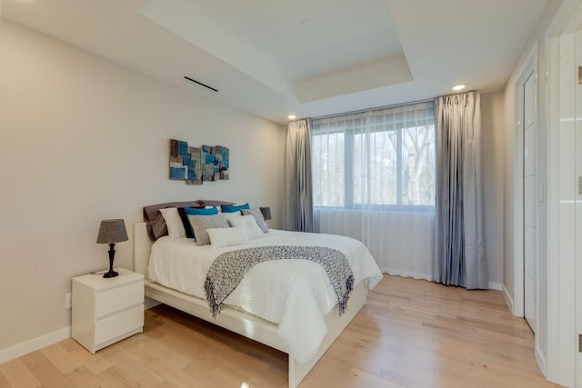 bedroom featuring light hardwood / wood-style floors and a raised ceiling