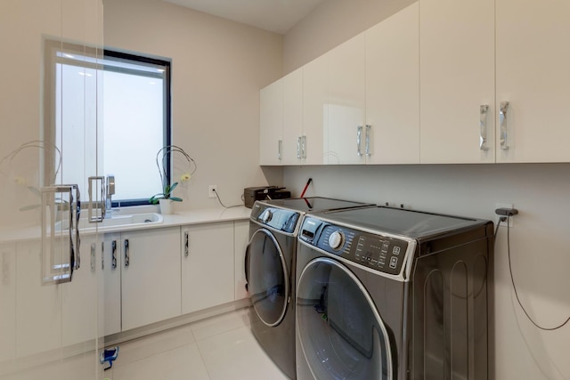 clothes washing area featuring cabinets, light tile patterned floors, separate washer and dryer, and sink