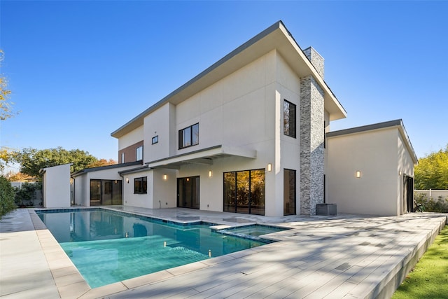 back of property with a swimming pool with hot tub and a patio area