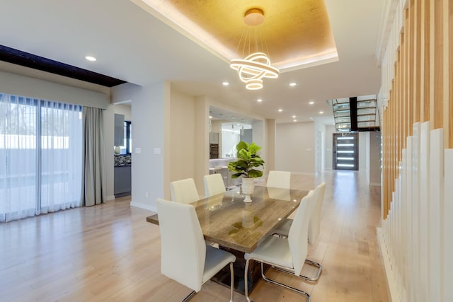 dining area featuring light hardwood / wood-style floors, a tray ceiling, and a notable chandelier