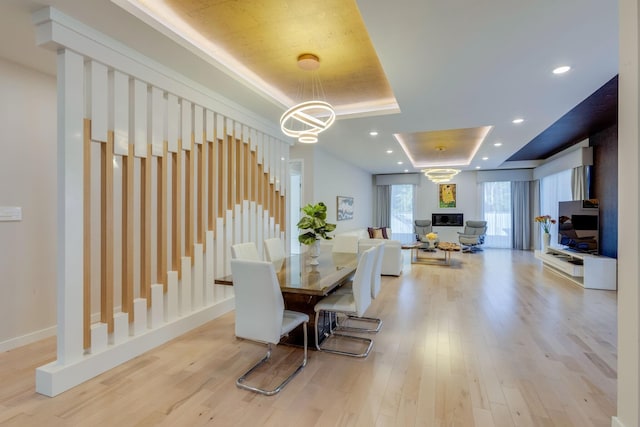 dining space featuring a chandelier, light wood-type flooring, and a tray ceiling