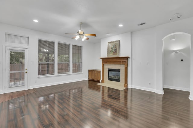 unfurnished living room featuring ceiling fan, a tile fireplace, and dark hardwood / wood-style floors