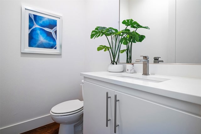 bathroom with toilet, hardwood / wood-style floors, and vanity