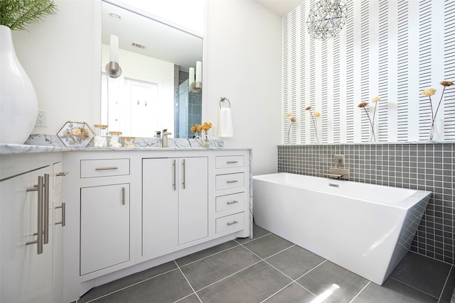 bathroom with vanity, a bathing tub, tile patterned floors, and tile walls