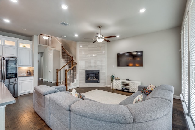 living room featuring ceiling fan, a fireplace, and dark hardwood / wood-style floors