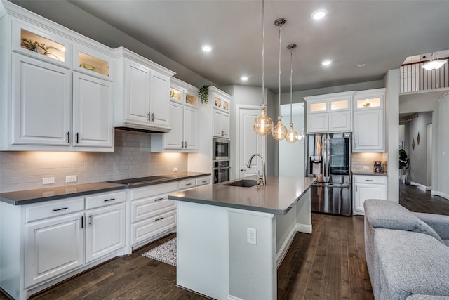 kitchen featuring a center island with sink, pendant lighting, white cabinetry, appliances with stainless steel finishes, and dark hardwood / wood-style flooring