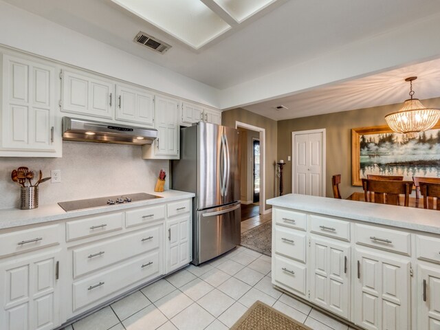 kitchen featuring black electric cooktop, white cabinetry, decorative light fixtures, a notable chandelier, and stainless steel refrigerator