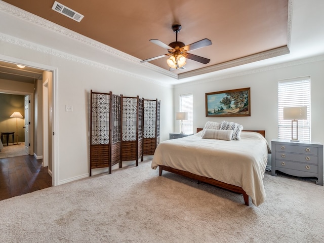 bedroom featuring ornamental molding, hardwood / wood-style floors, a tray ceiling, and ceiling fan