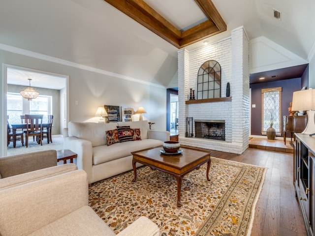 living room with a notable chandelier, hardwood / wood-style flooring, high vaulted ceiling, and a fireplace