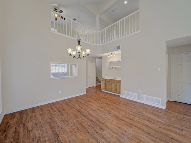 interior space with ceiling fan with notable chandelier, sink, hardwood / wood-style floors, and a towering ceiling