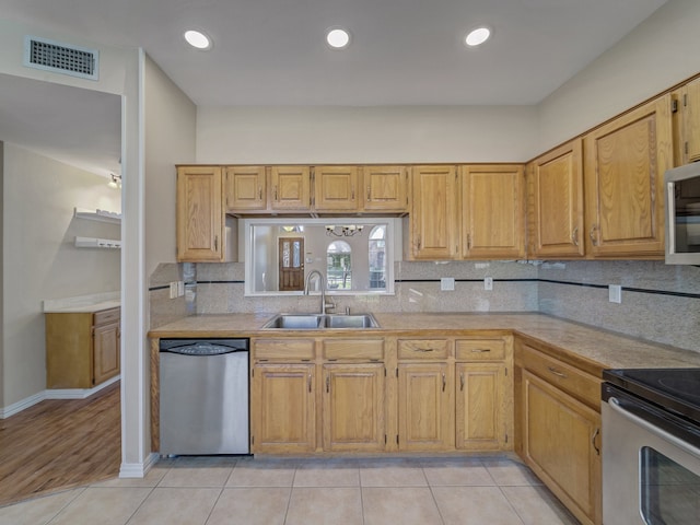 kitchen featuring sink, light tile patterned floors, backsplash, and appliances with stainless steel finishes