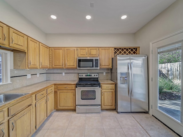 kitchen featuring light tile patterned floors, sink, appliances with stainless steel finishes, decorative backsplash, and light brown cabinets