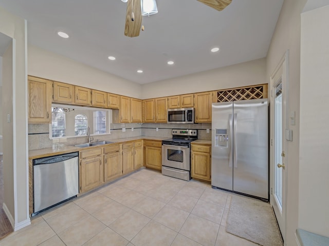 kitchen featuring light brown cabinetry, sink, tasteful backsplash, light tile patterned floors, and stainless steel appliances