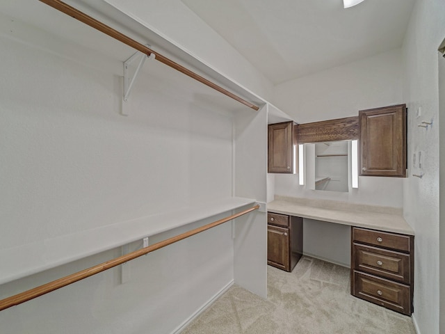 walk in closet with light carpet and built in desk