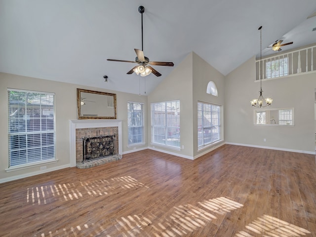 unfurnished living room with hardwood / wood-style flooring, ceiling fan with notable chandelier, and high vaulted ceiling