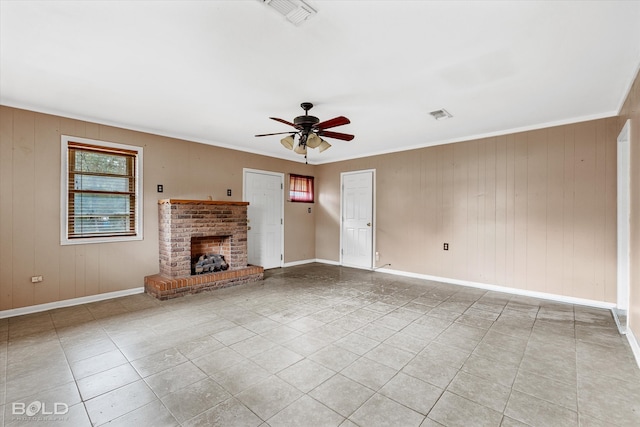 unfurnished living room with ceiling fan, wood walls, light tile patterned floors, and a fireplace