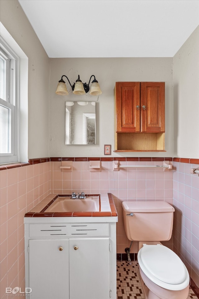 bathroom featuring vanity, tile walls, and toilet