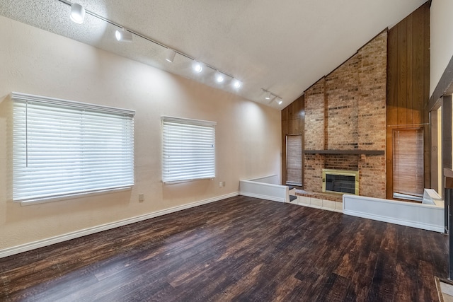 unfurnished living room featuring a healthy amount of sunlight, a brick fireplace, a textured ceiling, and high vaulted ceiling