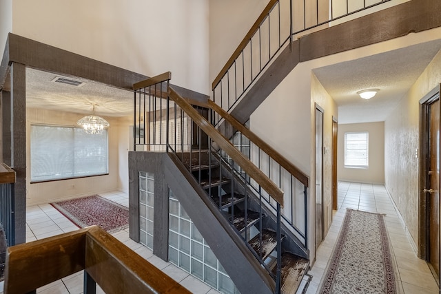 stairs featuring a textured ceiling, a chandelier, and tile patterned floors