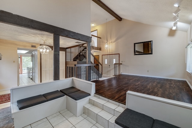 interior space with lofted ceiling with beams, a textured ceiling, light hardwood / wood-style flooring, and a chandelier