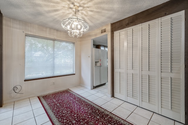 interior space with a textured ceiling, light tile patterned flooring, and a chandelier