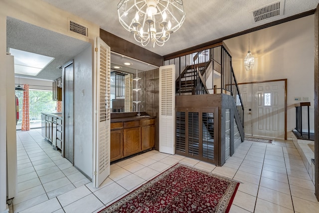 bathroom featuring a textured ceiling, tile patterned floors, vanity, crown molding, and an inviting chandelier