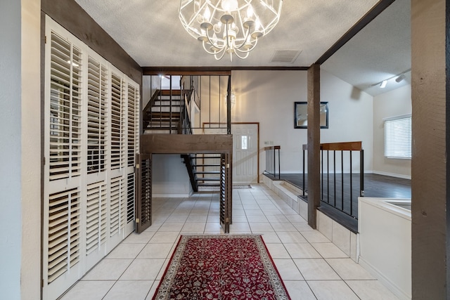 interior space with an inviting chandelier, lofted ceiling, a textured ceiling, and light tile patterned floors