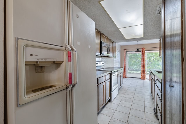 kitchen featuring a textured ceiling, white appliances, and light tile patterned floors