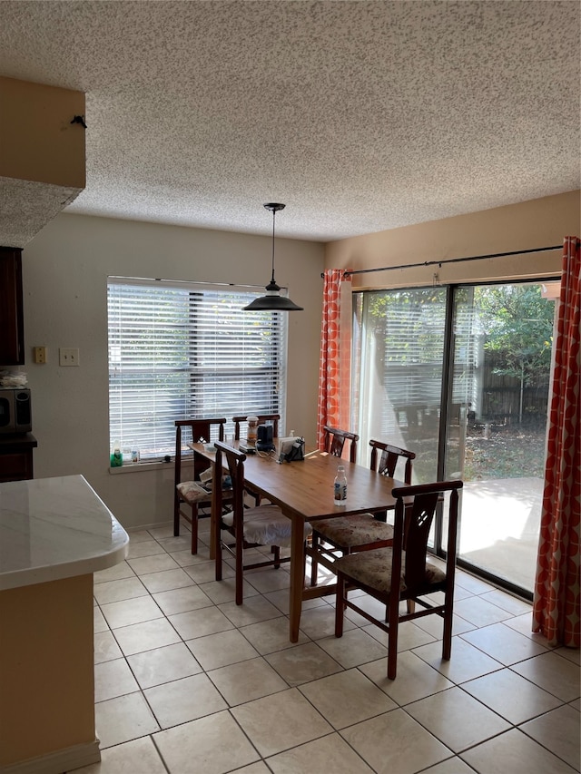 dining space featuring a wealth of natural light, a textured ceiling, and light tile patterned floors