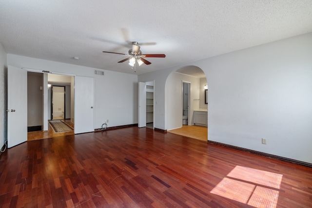 empty room featuring a textured ceiling, wood-type flooring, built in features, and ceiling fan