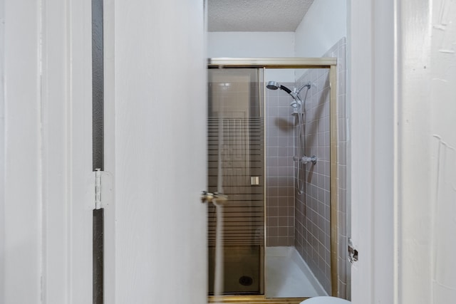 bathroom with toilet, a textured ceiling, and an enclosed shower