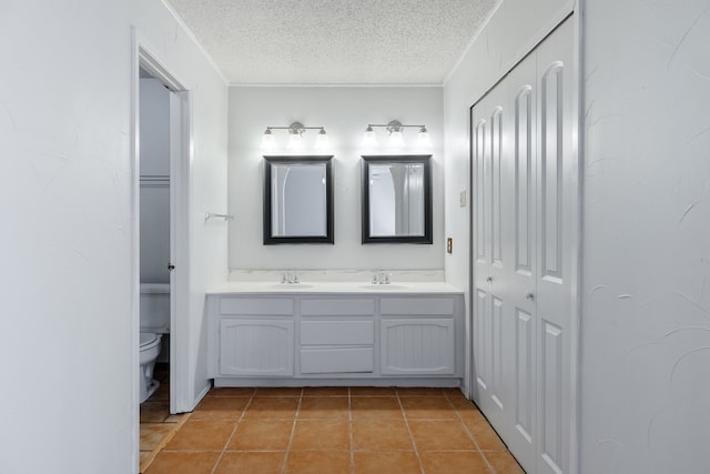 bathroom with vanity, toilet, tile patterned floors, and a textured ceiling