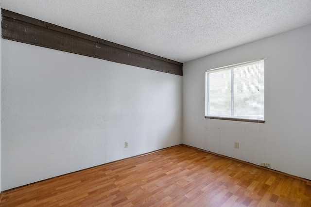 unfurnished room featuring a textured ceiling and light wood-type flooring