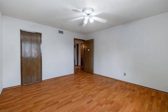 unfurnished bedroom featuring light hardwood / wood-style flooring, a textured ceiling, a closet, and ceiling fan