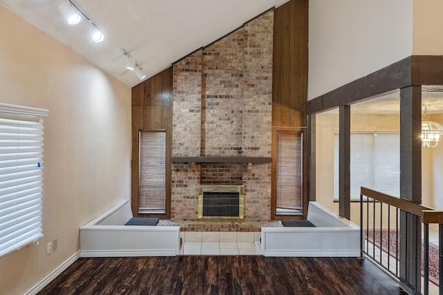 unfurnished living room with hardwood / wood-style floors, track lighting, a fireplace, and high vaulted ceiling