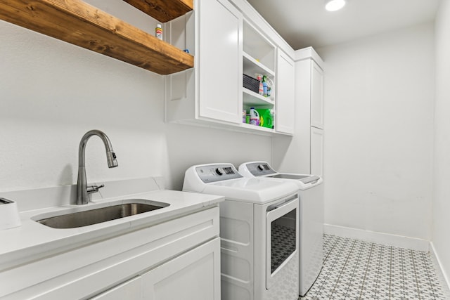 clothes washing area featuring sink, cabinets, and washer and clothes dryer