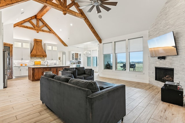 living room with beam ceiling, high vaulted ceiling, light hardwood / wood-style flooring, and a fireplace