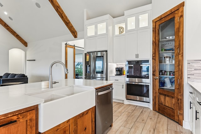 kitchen featuring stainless steel appliances, sink, a barn door, and white cabinets