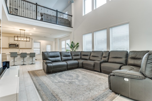 living room featuring an inviting chandelier, a high ceiling, plenty of natural light, and light wood-type flooring