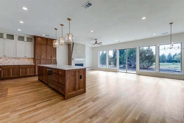 kitchen with light hardwood / wood-style flooring, hanging light fixtures, a center island with sink, and sink