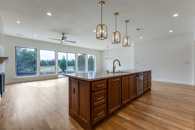 kitchen with stainless steel appliances, decorative light fixtures, custom range hood, a large island with sink, and light hardwood / wood-style flooring