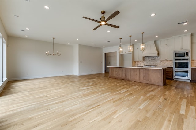 kitchen featuring white cabinetry, a large island, pendant lighting, light hardwood / wood-style floors, and custom exhaust hood