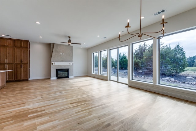 spare room with ceiling fan with notable chandelier, light hardwood / wood-style floors, and plenty of natural light