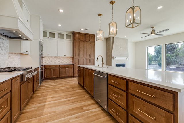 kitchen featuring white cabinets, stainless steel gas cooktop, custom range hood, backsplash, and light hardwood / wood-style flooring