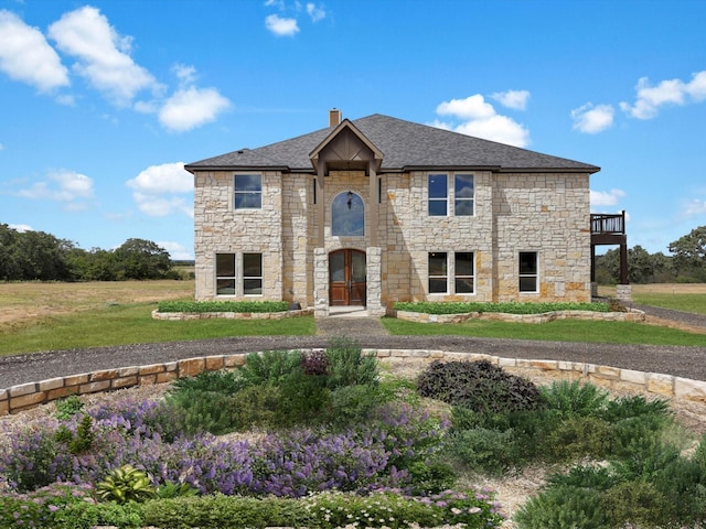 view of front facade featuring a front lawn, a chimney, and stone siding