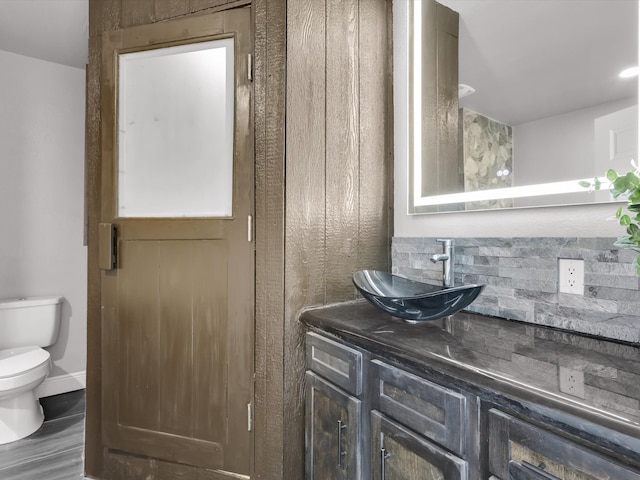 bathroom featuring toilet, backsplash, vanity, and hardwood / wood-style floors