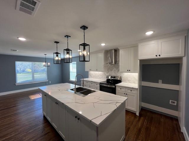 kitchen featuring stainless steel electric range oven, a kitchen island with sink, sink, wall chimney range hood, and white cabinetry